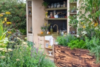 Outdoor kitchen area with raised beds containing herbs, vegetables and perennials