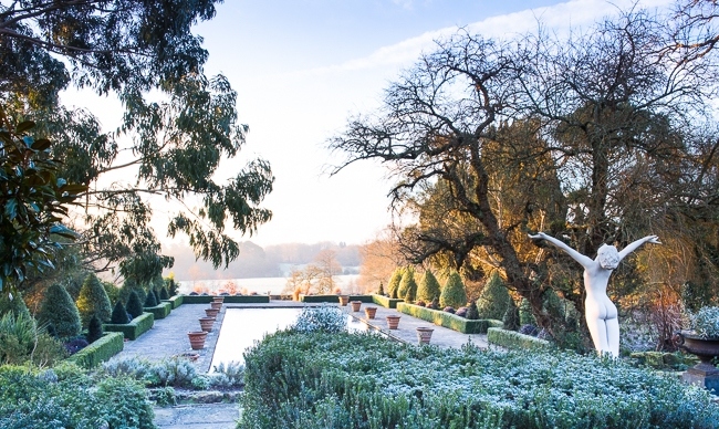 Winter in the formal Italianate garden at Borde Hill with a nude statue of a woman with outstretched arms in foreground