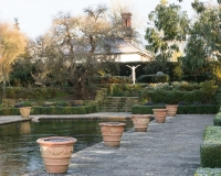 Terracotta containers around the edge of the frozen pool in the Italianate garden with rill in background