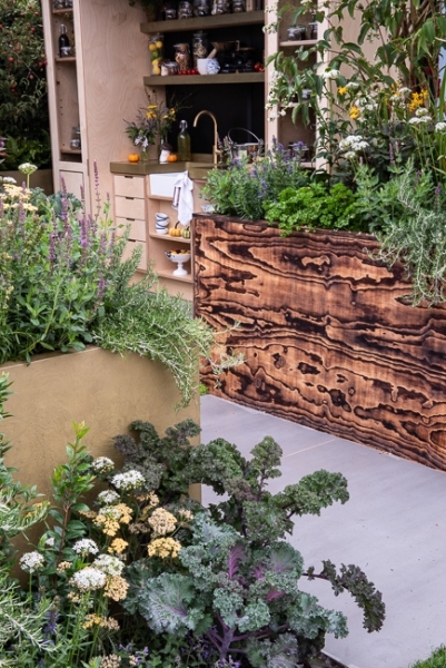 Outdoor kitchen area with raised beds containing herbs, vegetables and perennials