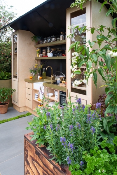 Outdoor kitchen area with raised beds containing herbs, vegetables and perennials