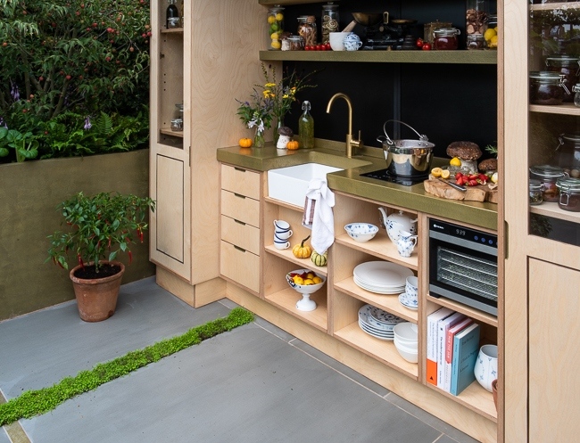 Outdoor kitchen area with raised beds containing herbs, vegetables and perennials
