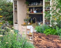 Outdoor kitchen area with raised beds containing herbs, vegetables and perennials