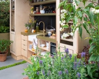 Outdoor kitchen area with raised beds containing herbs, vegetables and perennials