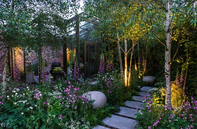 Lighting in a woodland garden beside a rill running around the edge of a conservatory