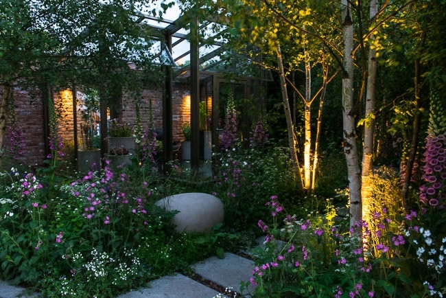 Lighting in a woodland garden beside a rill running around the edge of a conservatory