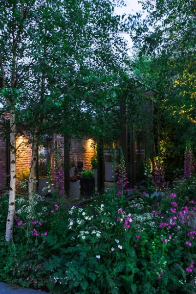 Lighting in a woodland garden beside a rill running around the edge of a conservatory