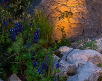 Lighting geometric basalt mounds in a contemporary mediterranean garden