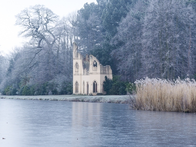 Painshill Park landscape garden overlooking the frozen lake with the Ruined Abbey in the background