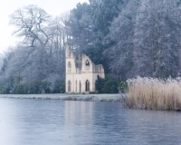 Painshill Park landscape garden overlooking the frozen lake with the Ruined Abbey in the background