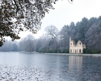 Painshill Park landscape garden overlooking the frozen lake with the Ruined Abbey in the background