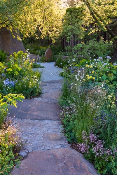 Blue sandstone pathway through borders of woodland plants and sandstone rocks