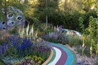 Coloured resin bonded pathway leads up to a sperical arbour in a chalk loving garden