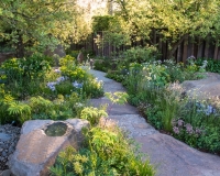 Blue sandstone pathway through borders of woodland plants and sandstone rocks