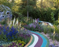 Coloured resin bonded pathway leads up to a sperical arbour in a chalk loving garden