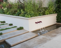 Pathway with stepping stone over a rill and water feature with raised beds behind