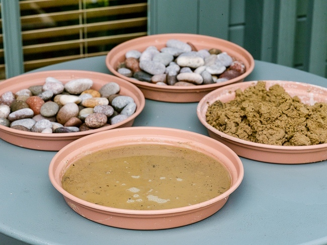 Making a pebble mosaic pattern. 1. Fill a circular plastic tray with about 1cm of wet sand and then pour water over it to just cover the sand